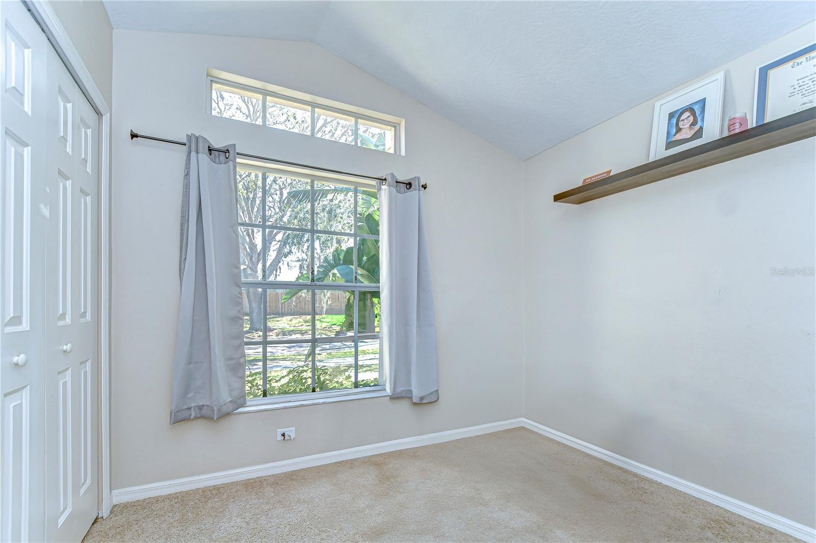 This sun-drenched bedroom boasts a stylish vaulted ceiling and a generous window, letting the Florida sunshine fill every corner.