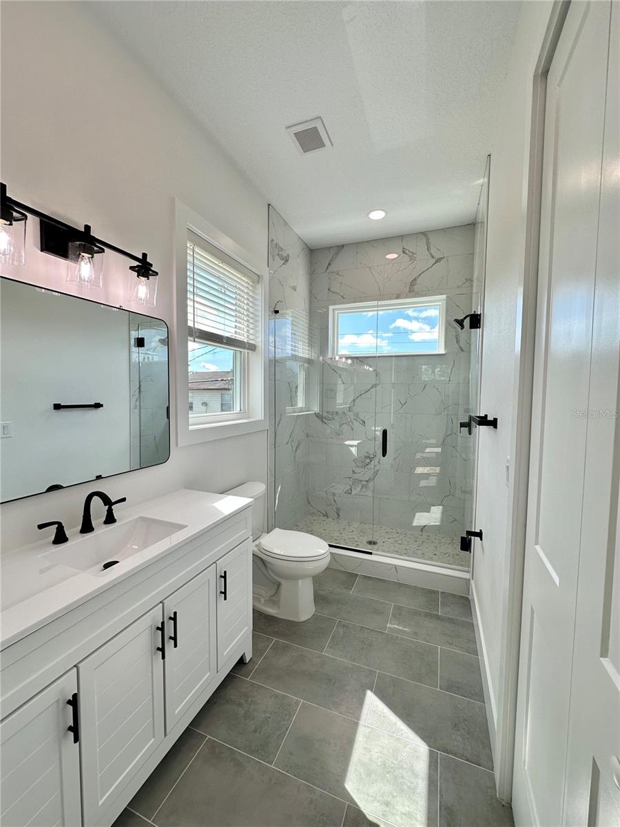 Bathroom with custom glass shower enclosure and 10 ft ceilings (ADU)