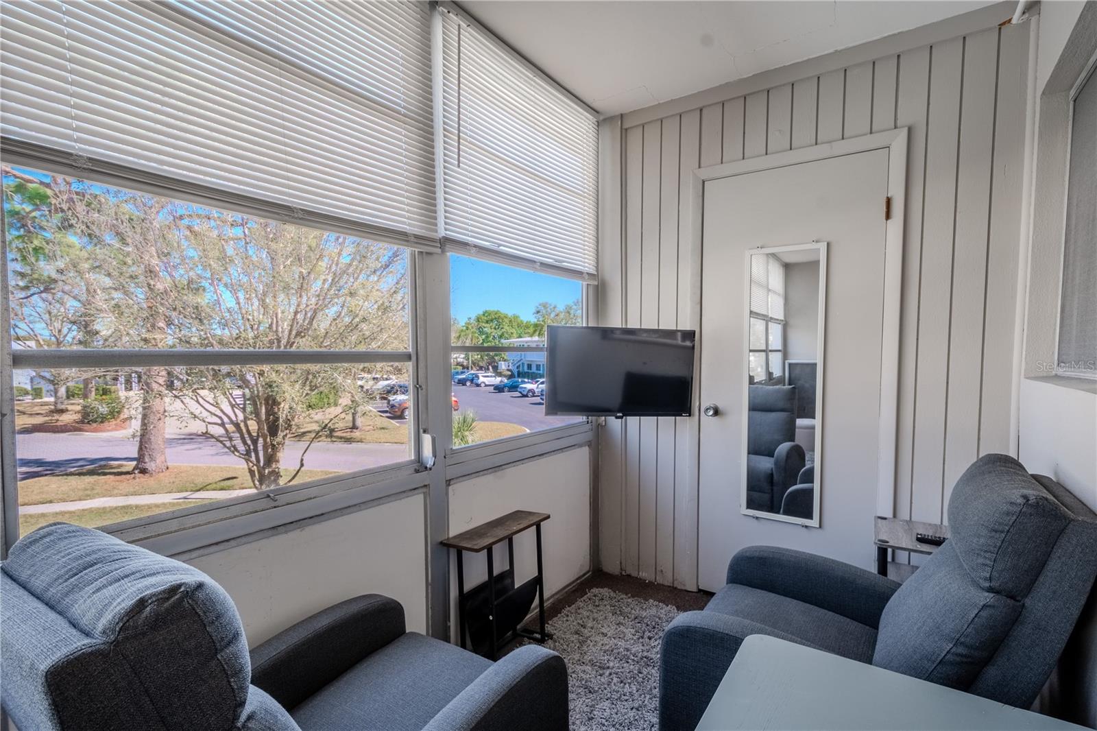 The lanai has 2 comfy chairs and a flat screen TV.