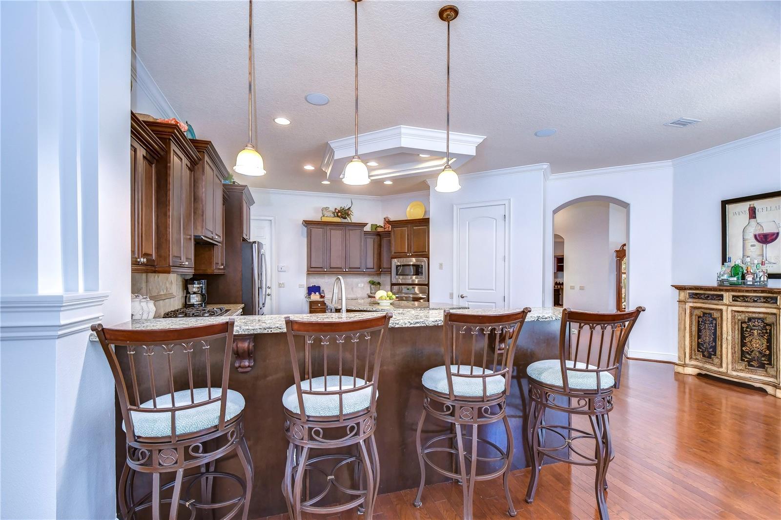 The spacious granite countertops and rich wooden cabinetry are perfect for culinary adventures or hosting friends around the chic breakfast bar.