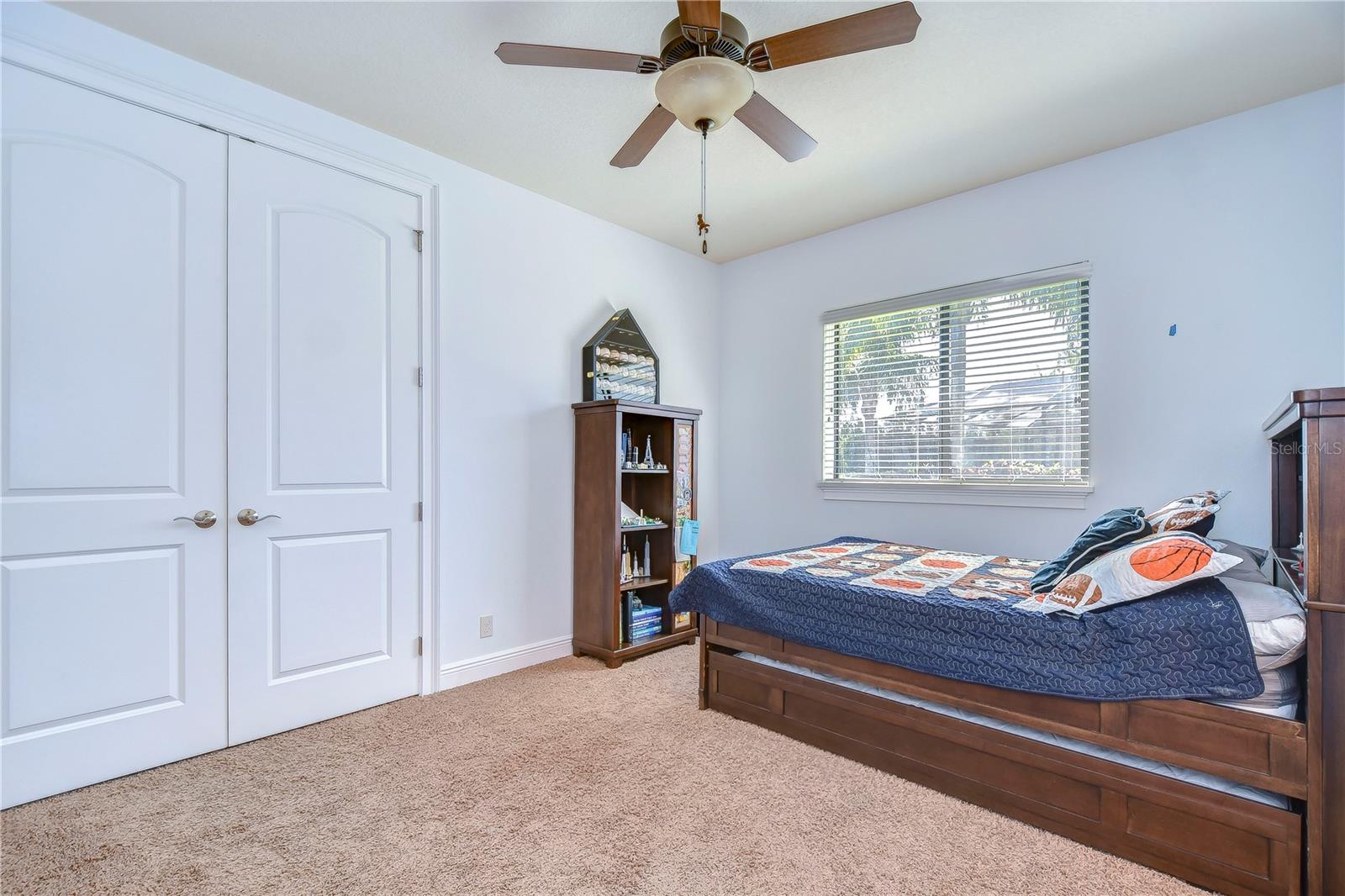 This inviting bedroom features plush carpeting and ample natural light, thanks to the large window with serene views.