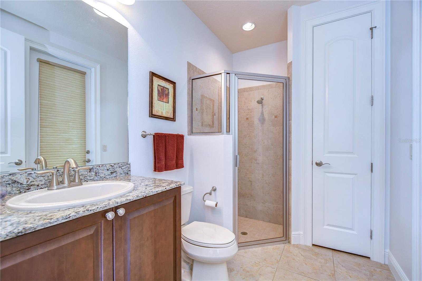 Step into serenity with this elegant bathroom, featuring a sleek granite countertop, modern fixtures, and a spacious glass shower.