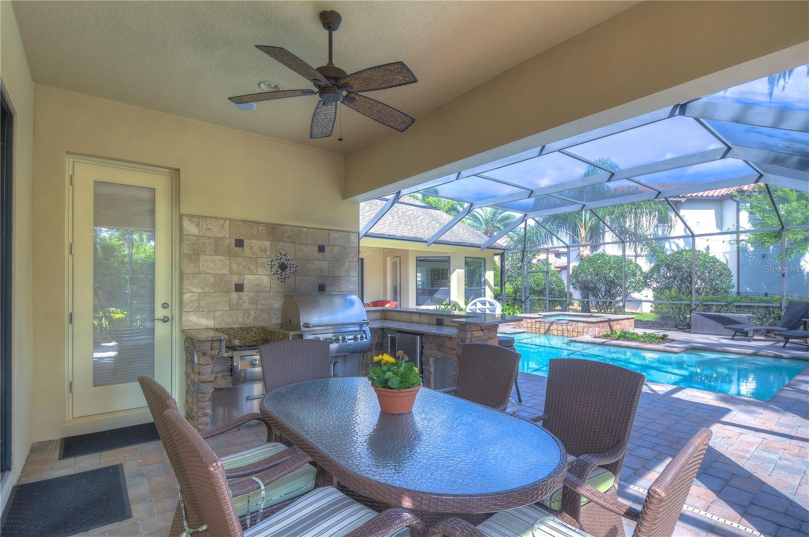 This stunning screened patio with an outdoor kitchen invites endless entertainment, whether you're grilling up a feast or enjoying a peaceful afternoon by the sparkling pool.