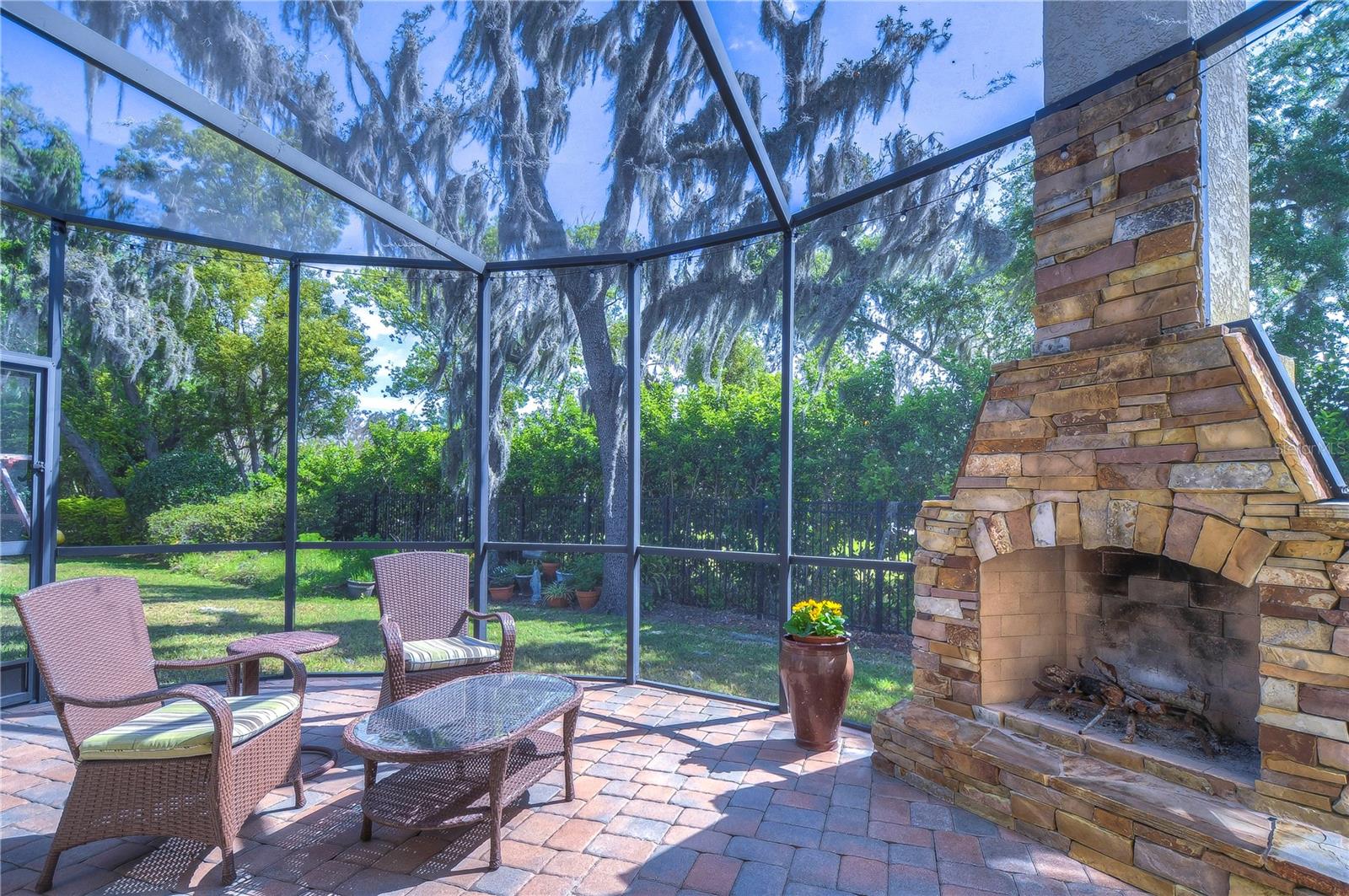 Step into your own backyard oasis featuring a beautifully screened-in patio with a rustic stone fireplace.