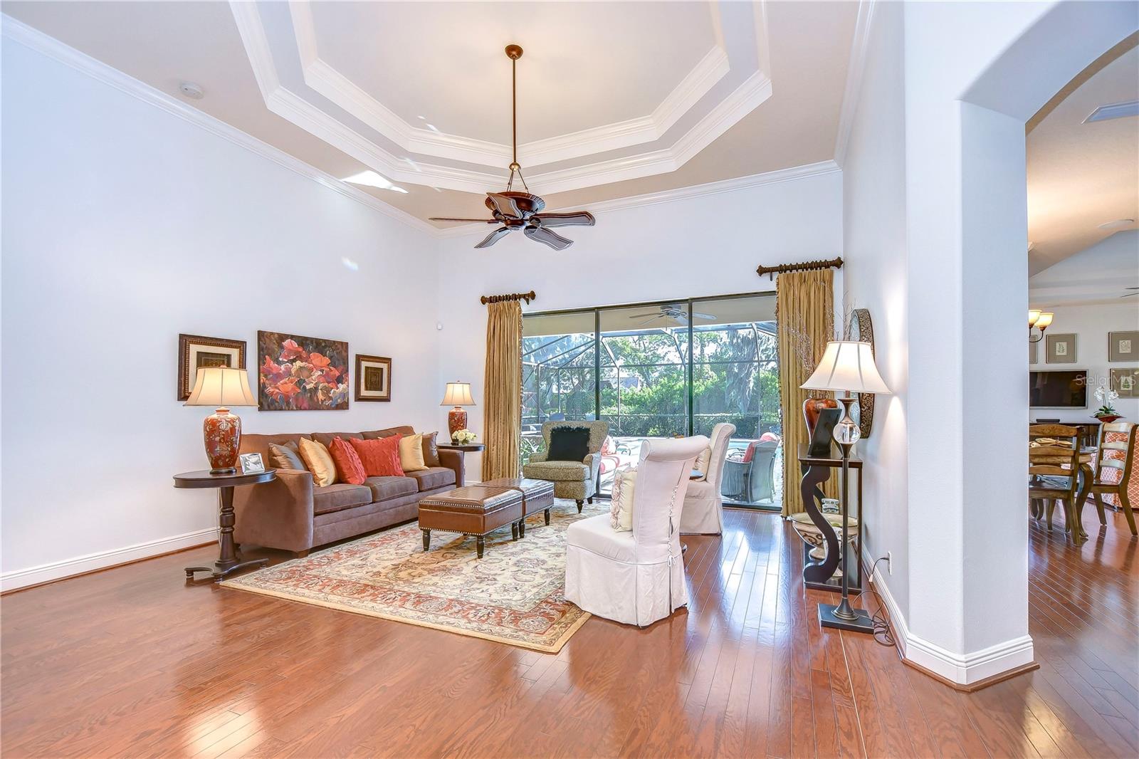 Bask in the natural light that floods this inviting formal living room, highlighted by elegant tray ceilings and gleaming hardwood floors.