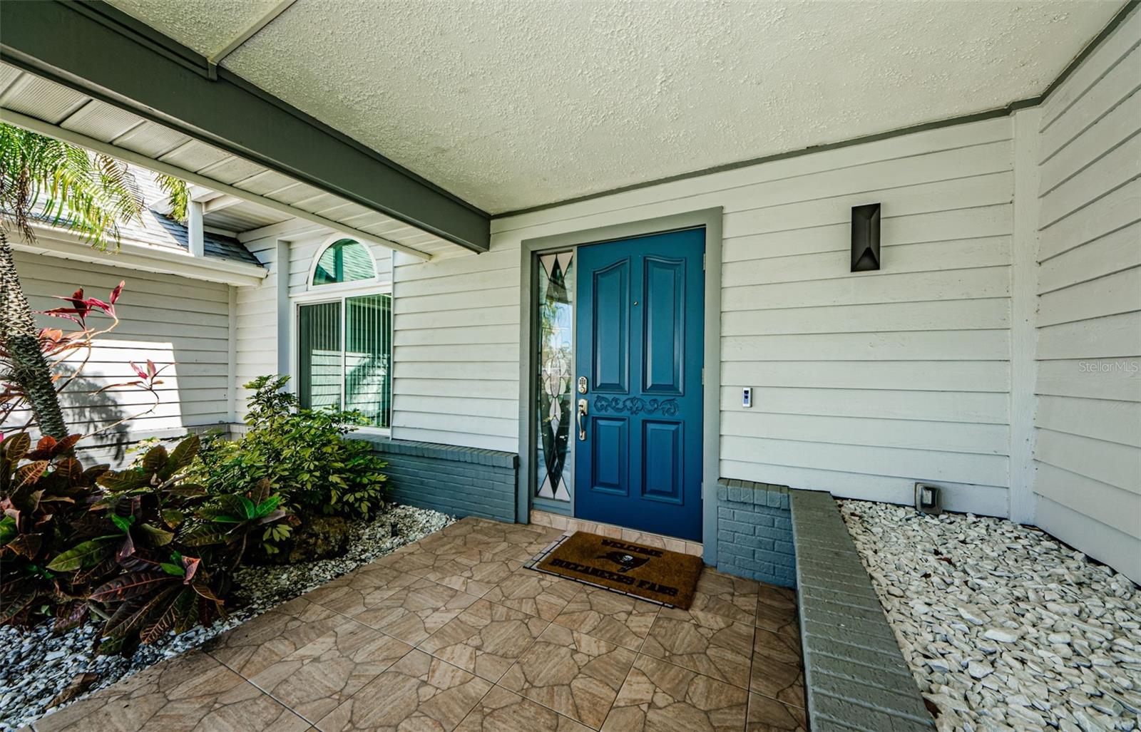 Nice comfortable size porch with artwork, attractive Royal Blue Entrance door with push key entry and side transom.  Two chairs and a wine and beer, and enjoy the view!