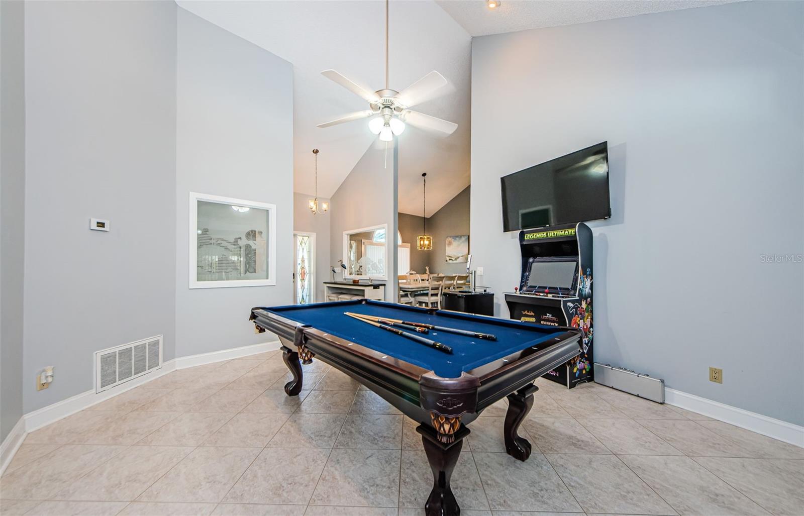 Large living room currently used as entertainment room, foyer and dining room seen in background.