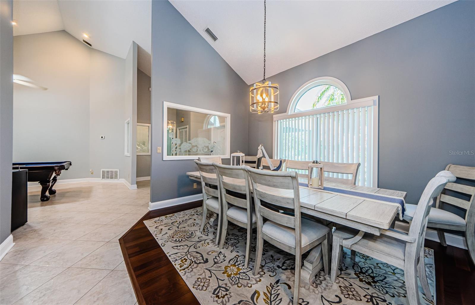 Formal dining area off living room with Cathedral ceiling, large window with smaller arch window above and cut out window glass setion to foyer,