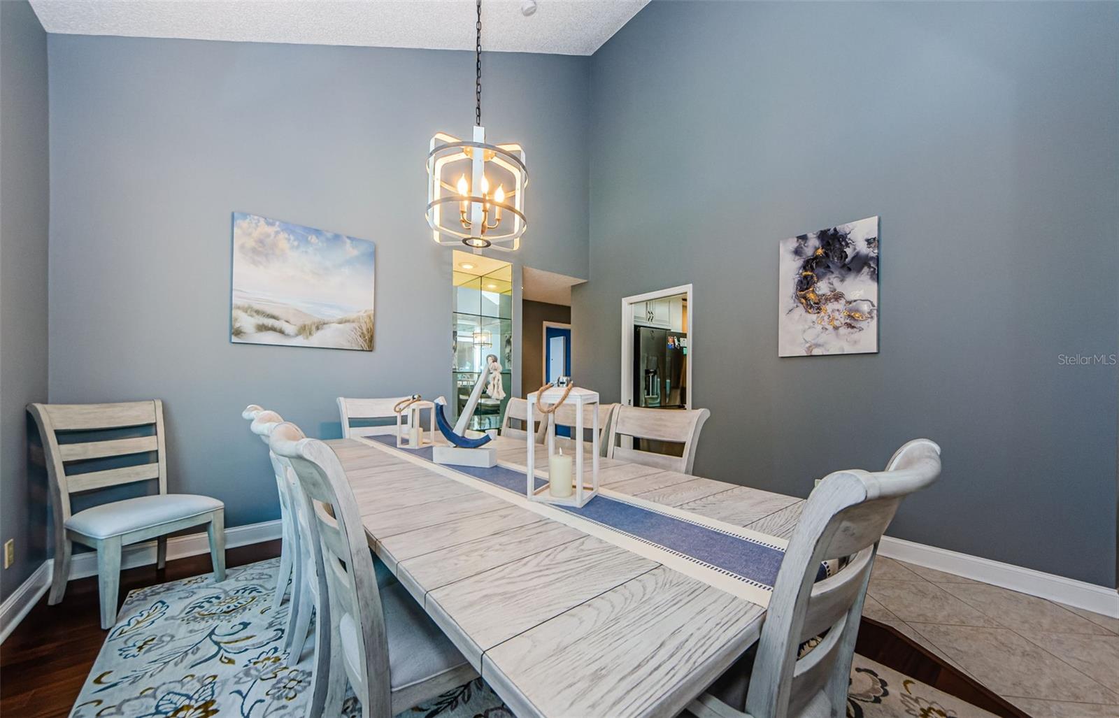 View 2 of formal dining room with glass mirrored inset with glass shelves, wood laminate flooring and porcelain tile surrounding and in the living room.