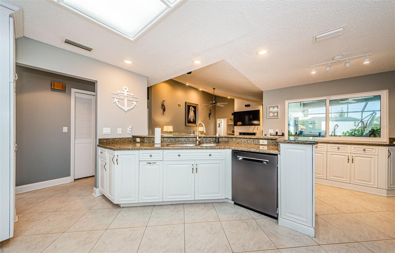 Kitchen has eating bar and serving buffet with double window overlooking outside kitchen and pool.