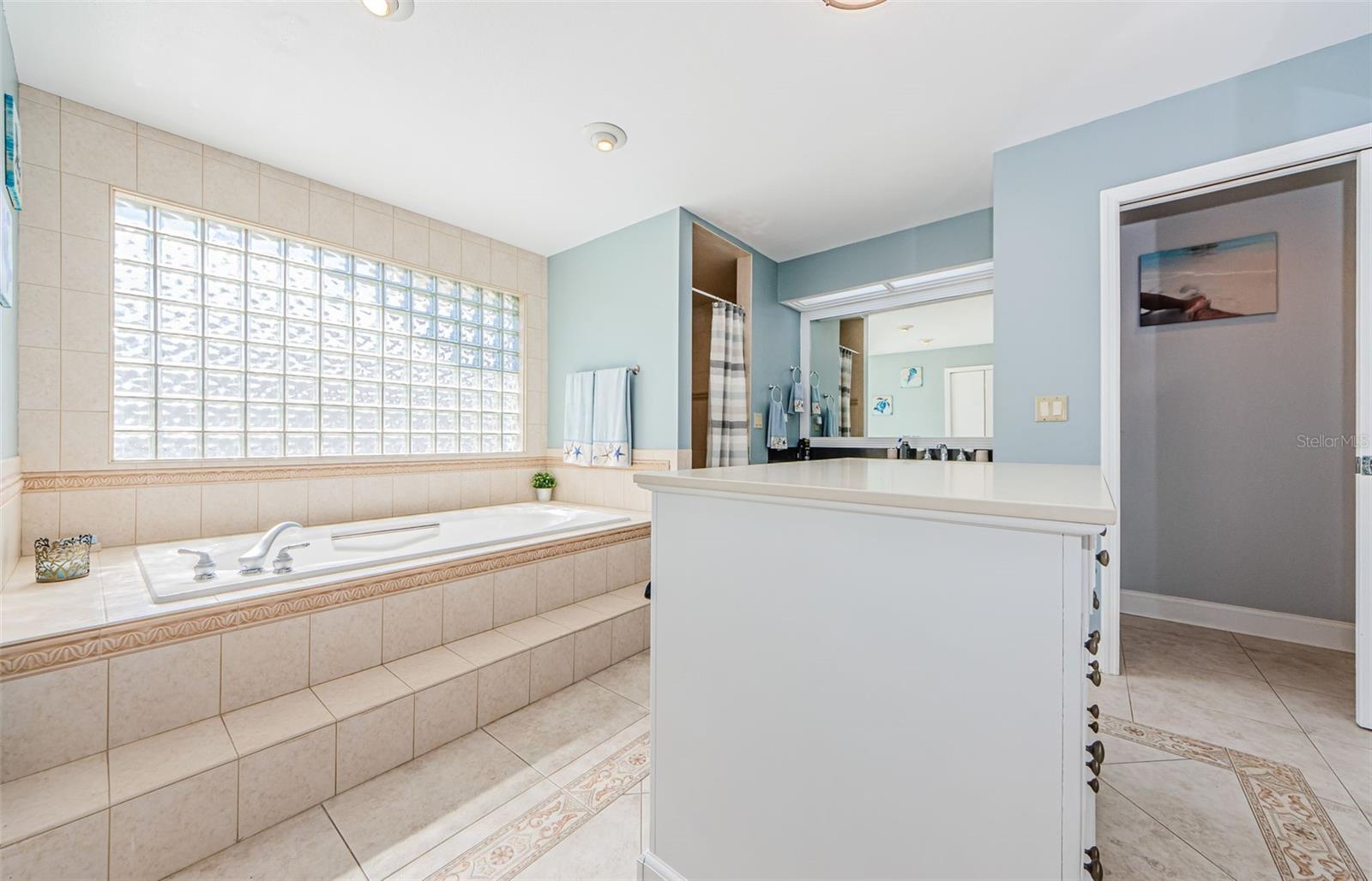 Soaking Garden Tub in the Primary Bathroom.  Separate shower, his and hers closets, and sink areas.