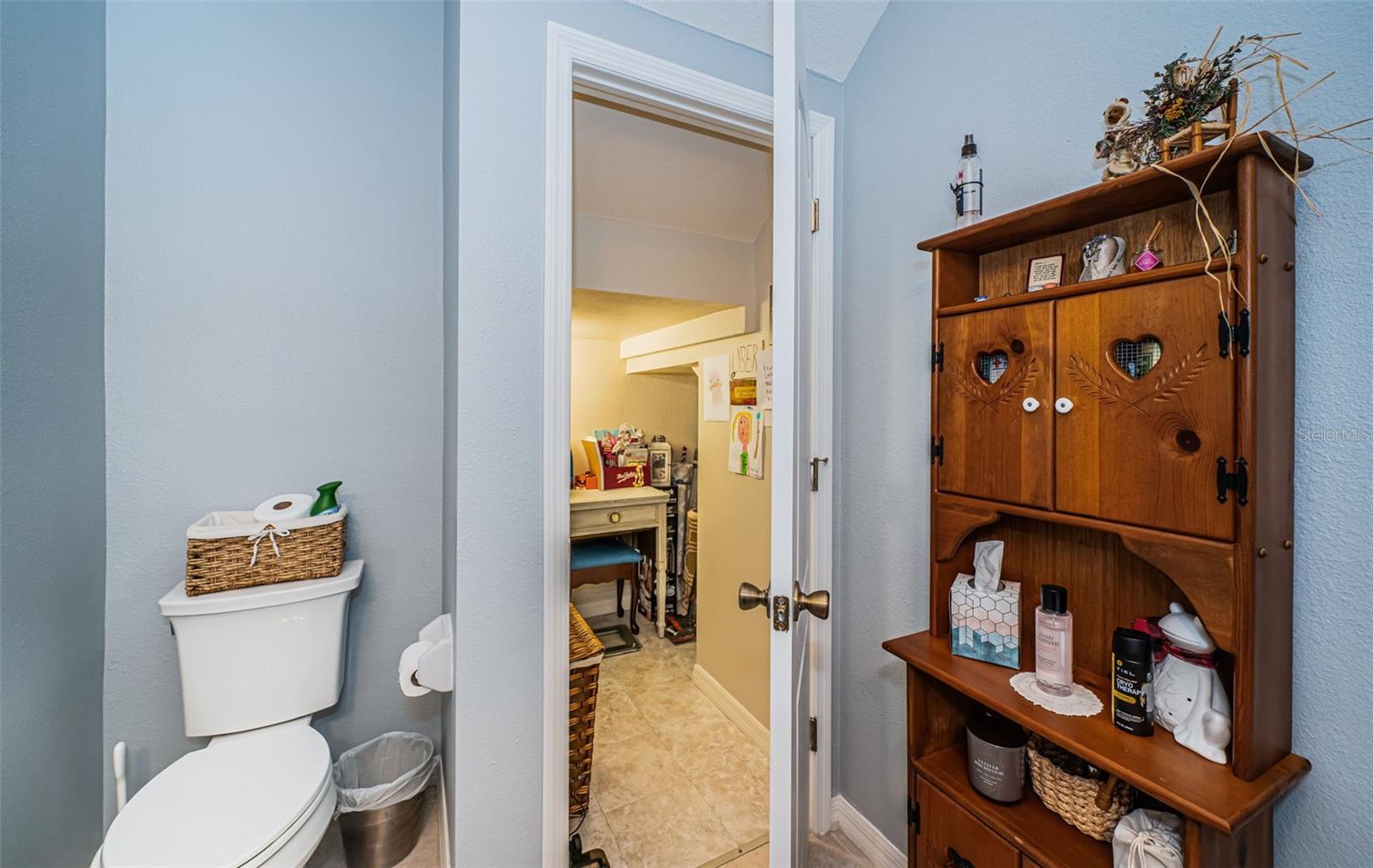 Half bathroom off of kitchen area leading to storage room under staircase