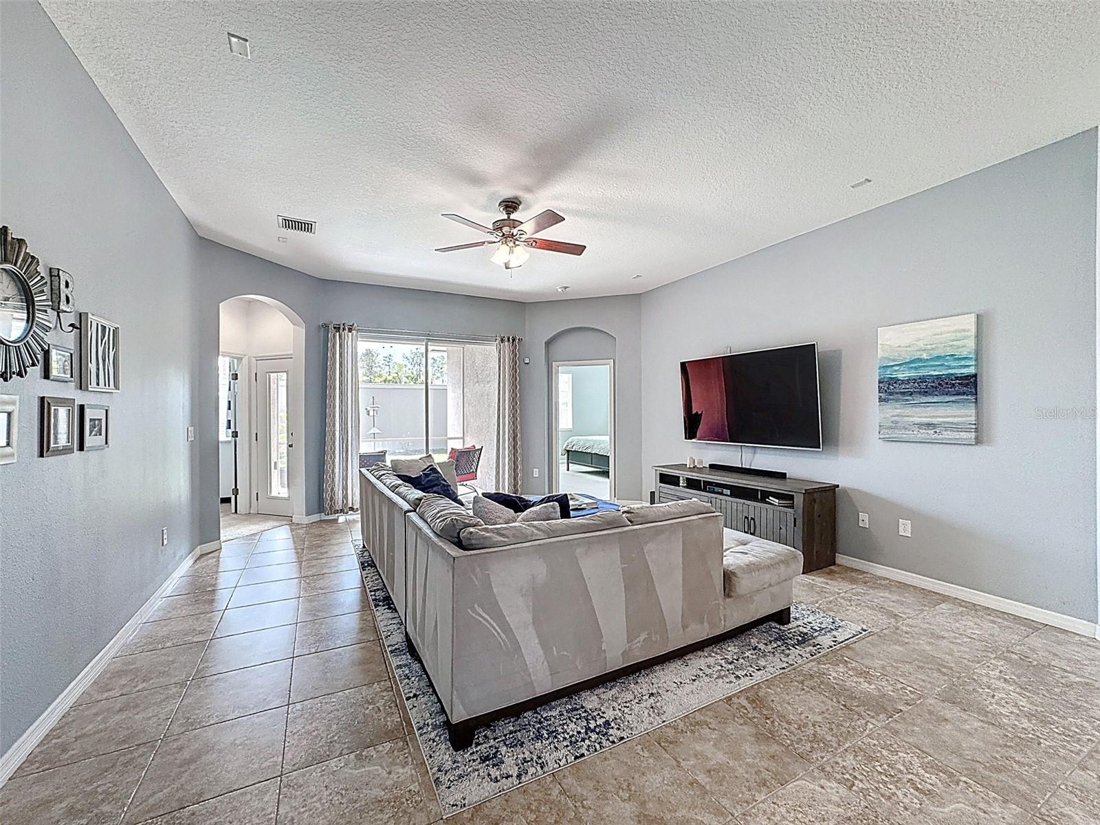 LIVING ROOM SLIDING GLASS DOORS TO THE BACKYARD AND PRIMARY BEDROOM SUITE TO THE RIGHT