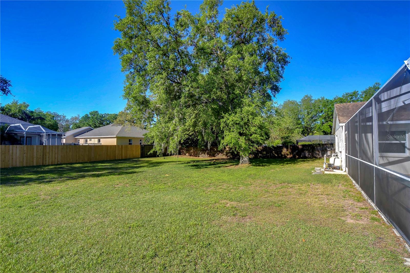 Discover the perfect canvas for outdoor dreams in this spacious backyard, adorned with a majestic tree offering shade and serenity.