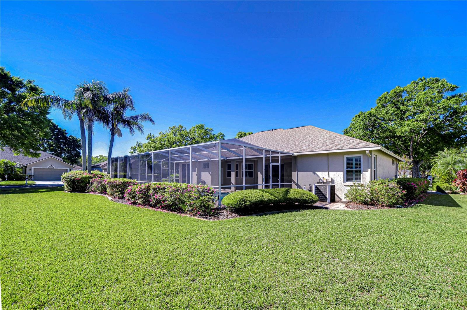 The lush, meticulously maintained yard offers a serene backdrop for weekend gatherings or simple relaxation under the swaying palm trees.