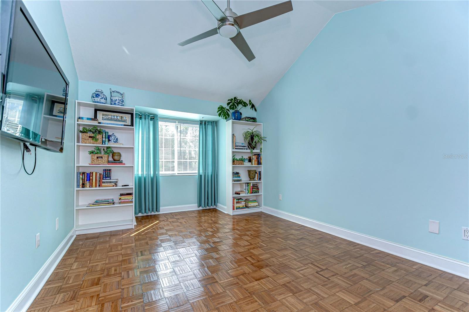 The sunlit bedroom features ample space and thoughtfully appointed built in book cases.