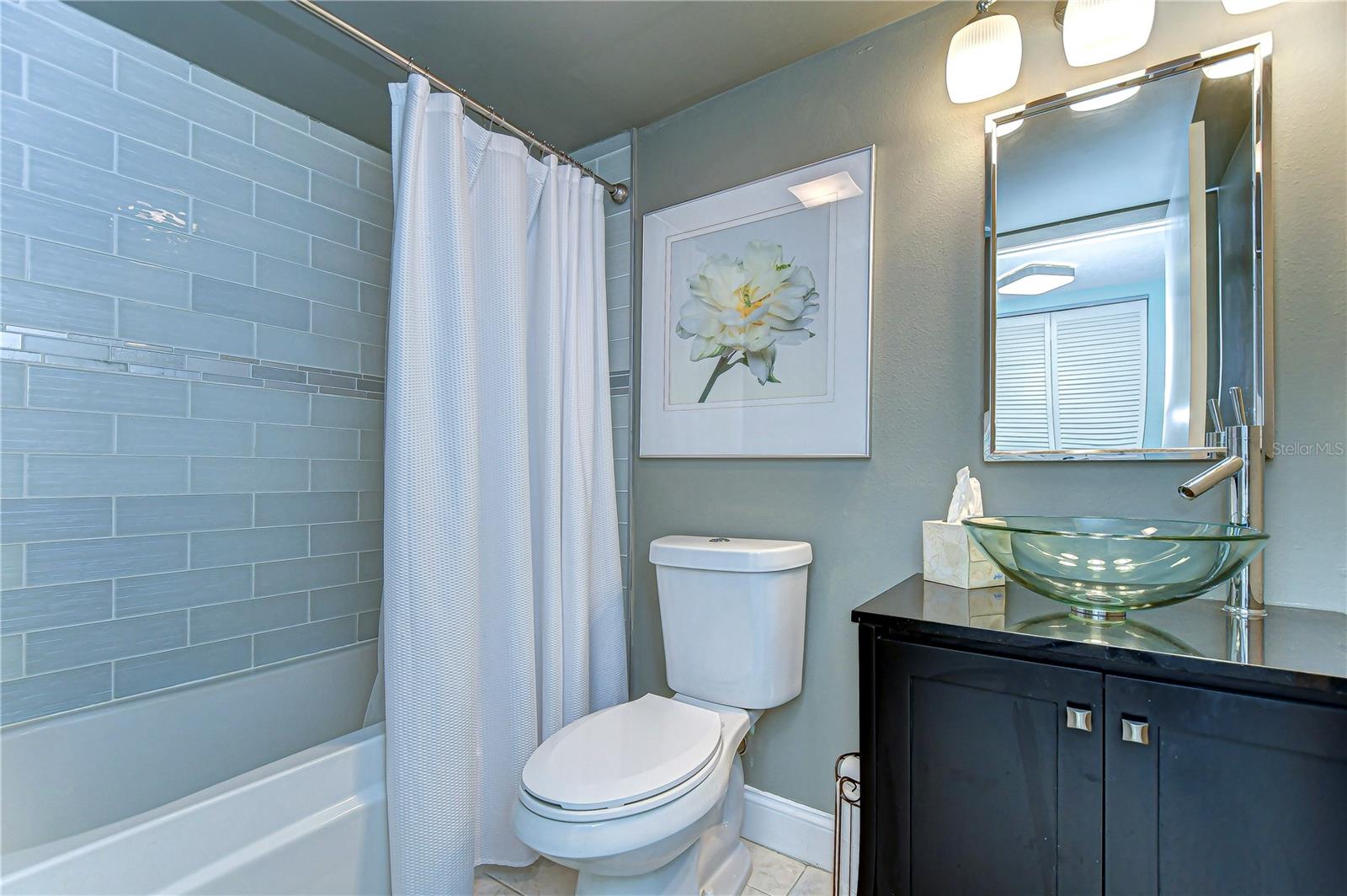 Step into tranquility with this bathroom's spa-like ambiance, complete with sleek glass tiles and a contemporary vessel sink.