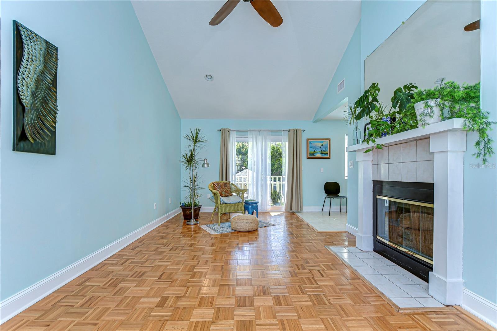 Admire the elegant fireplace, perfect for cozy evenings, while sunlight spills generously through the large windows, illuminating the striking parquet floors.