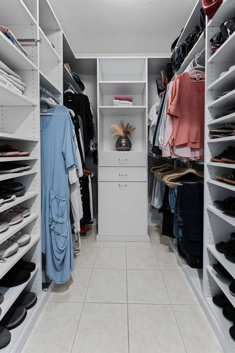 Primary bedroom closet has been customized, complete with a laundry bin