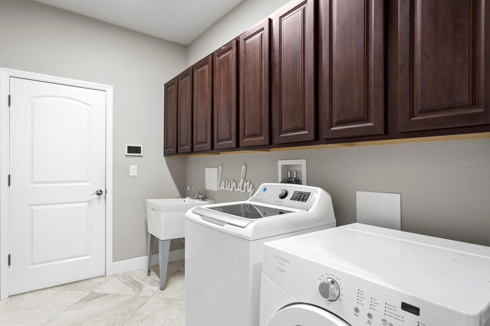 The oversized laundry room features cabinet storage, utility sink and washer/dryer included