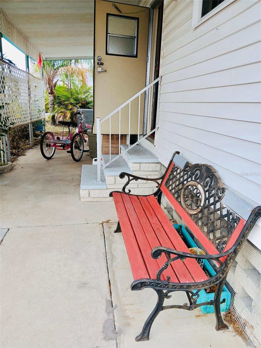 Bench by front door and covered patio area