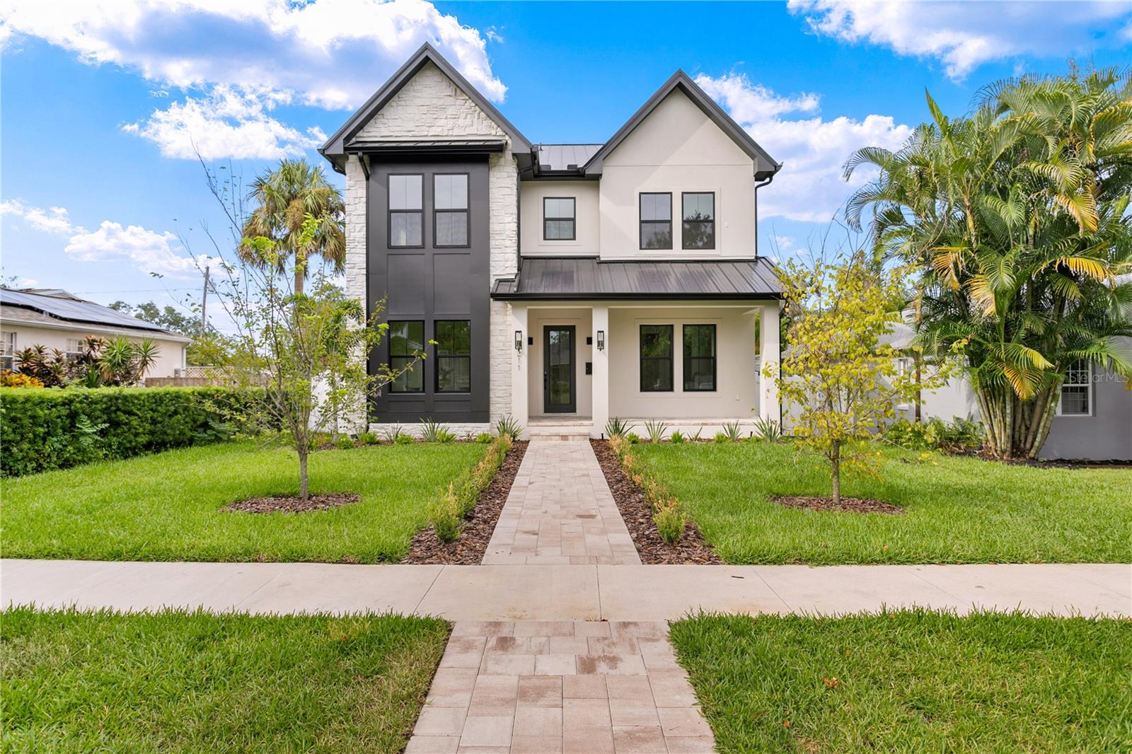 Front exterior with stone work, metal roof and natural gas lanterns.