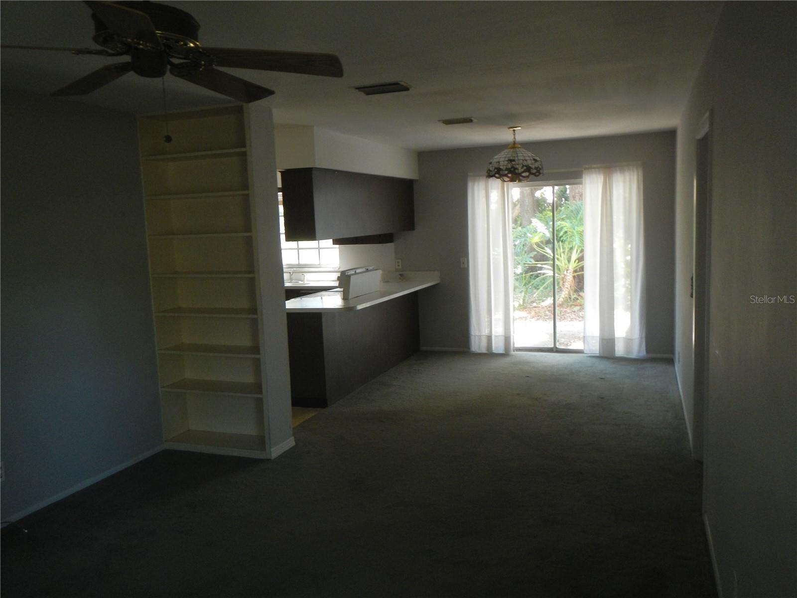 View from Family Room to Dinette and Kitchen.  Built in shelf, sliding glass door and door on right leading to half bath, Laundry Room and Garage.