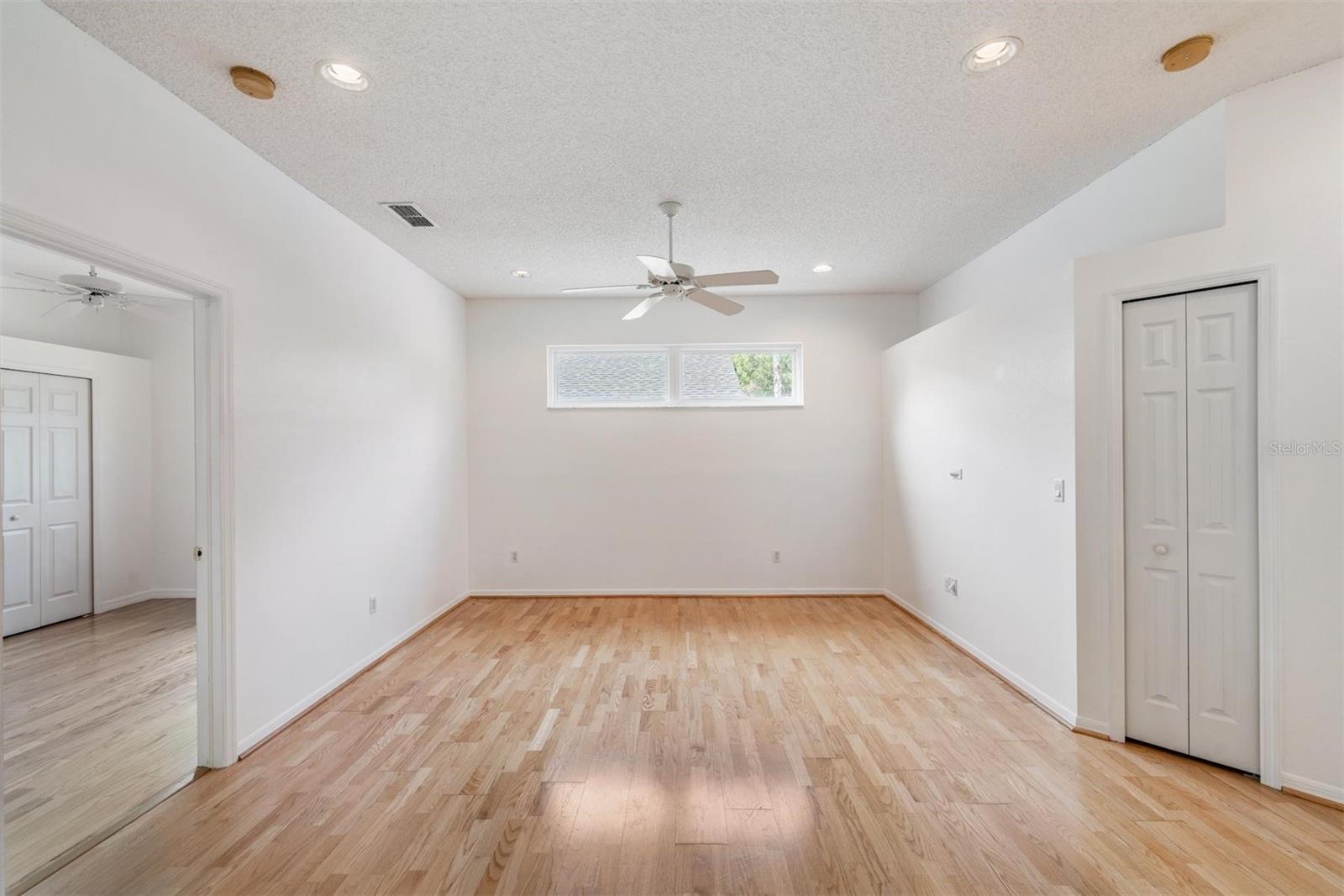 Family room with closet. Fan can lights and window.  Bedroom 3 is to the left.  Bedroom 2 is to the right with the community bathroom and exit to lanai.  Luxury Vinyl Plank flooring.