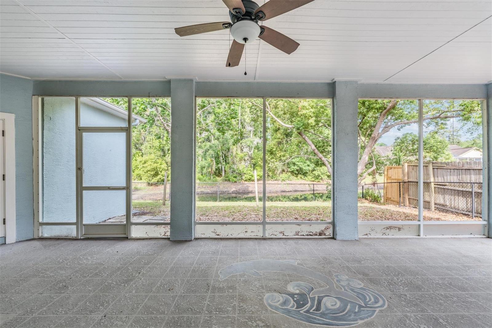 Three hurricane resistance double pane slider doors to screened lanai.  To the right is a 220 amp for a possible hot tub.  Beyond fence is a pond maintained by the HOA.