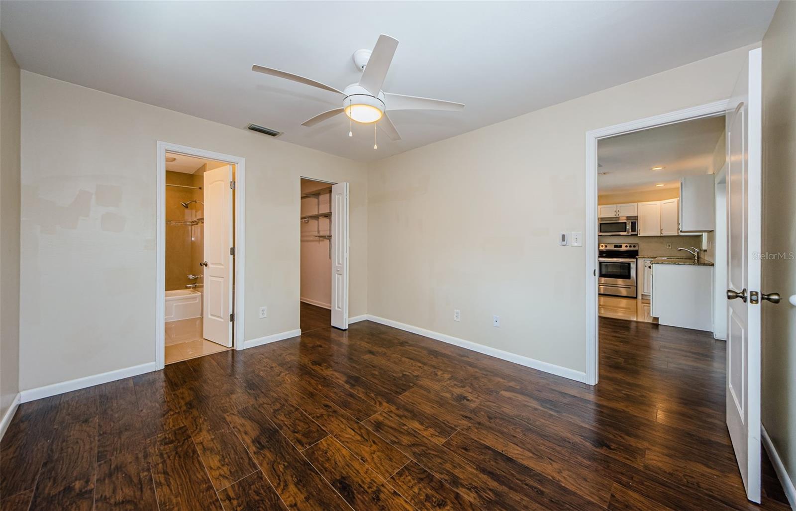 Additional angle of primary bedroom and view into kitchen.