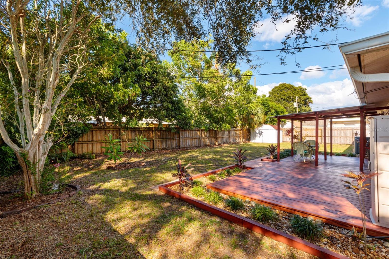 Shade trees surround the fenced yard