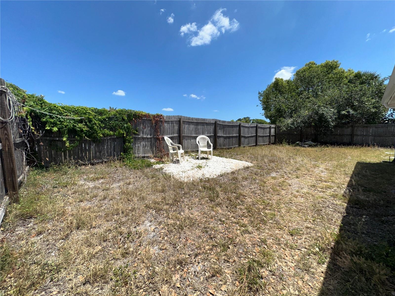 Large fenced in backyard with sitting area