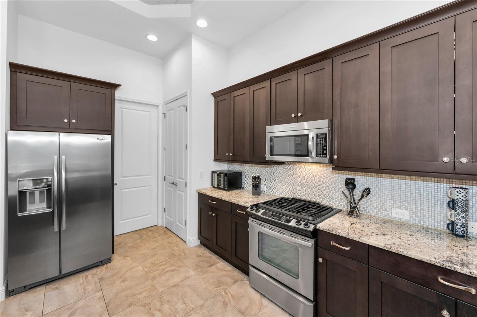 Stainless steel appliances - tile backsplash - custom cabinets
