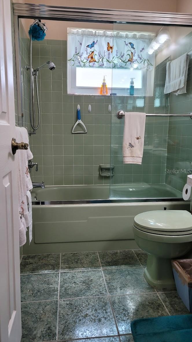 The guest bathroom shows well with the vintage green tiles accented with a glass shower door.