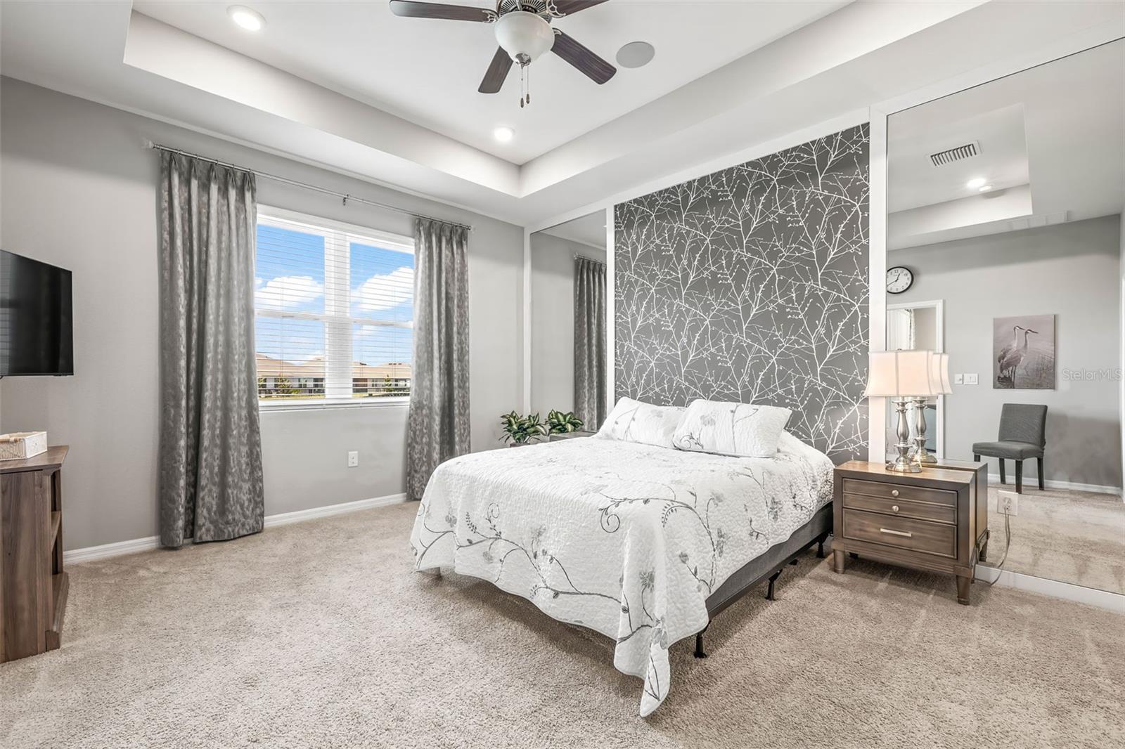 The primary suite has floor to ceiling accent wall, tray ceiling, backyard pond view, and ensuite bath/walk in closet.