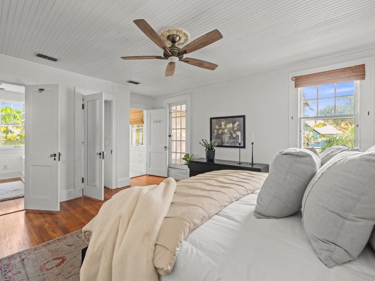 Primary bedroom with walk-in his and hers closets, private bathroom and door to screened porch overlooking the pool.
