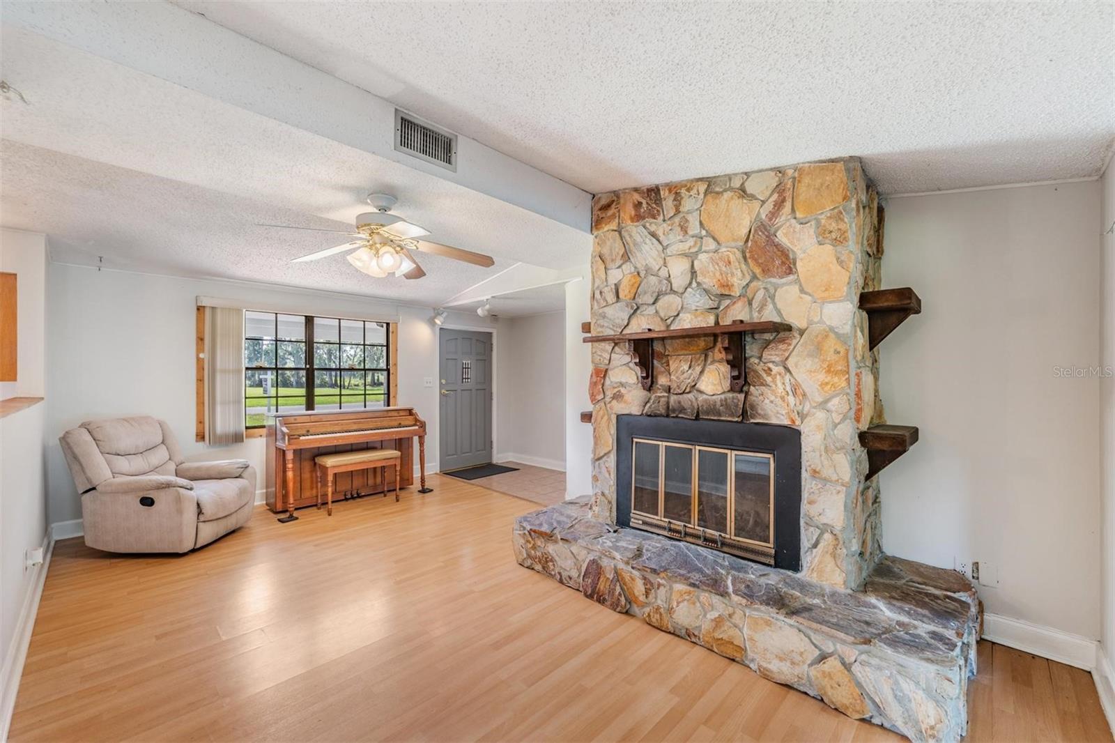 Living room with wood burning fireplace opens to kitchen and family room