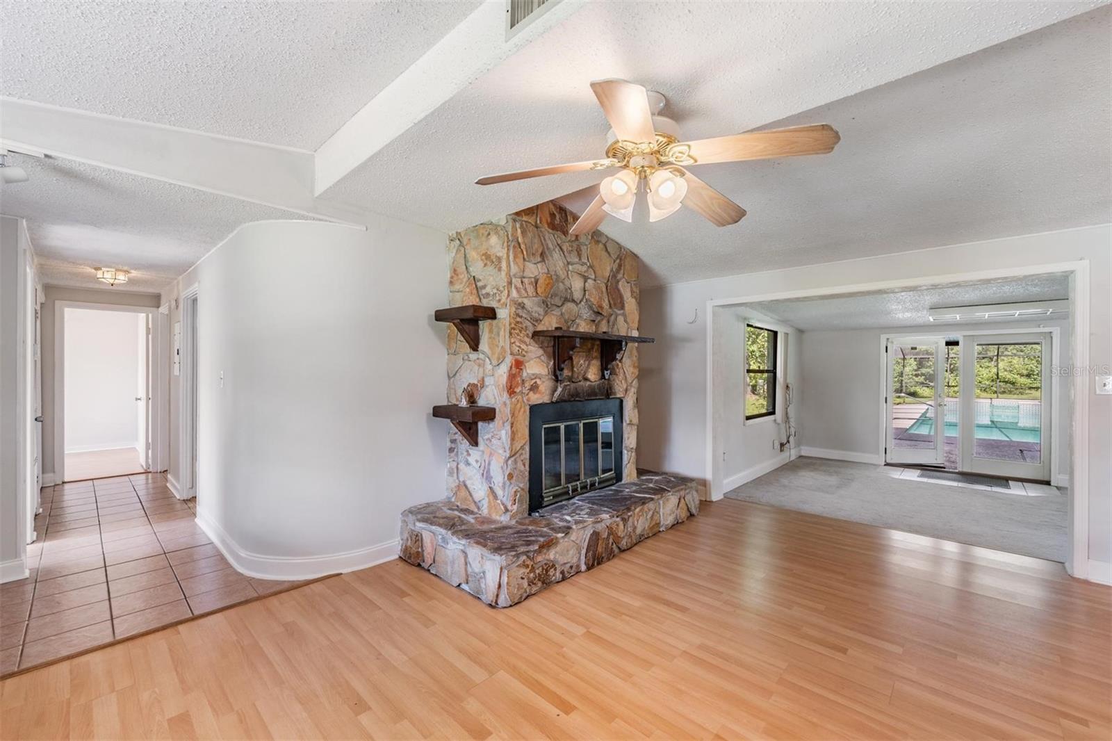 Living room with fireplace and hall to bedrooms. Family room opening to pool area.