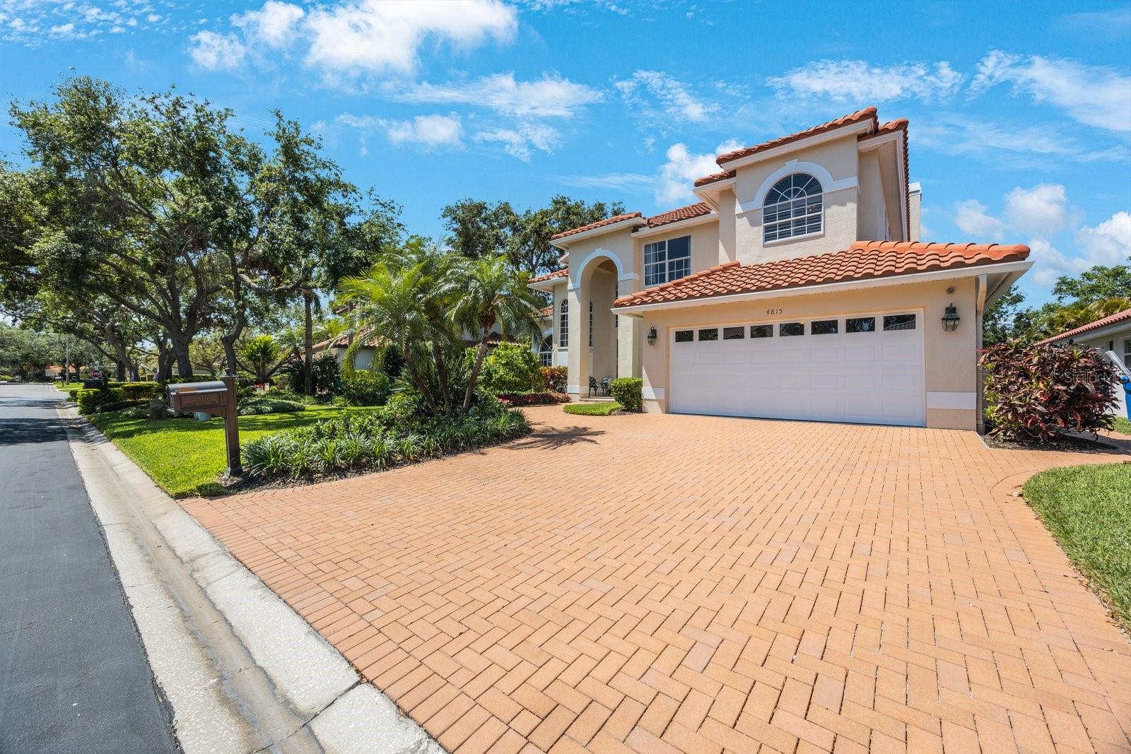 Brick walkway to right of driveway leads to garage door and trash hideaway.
