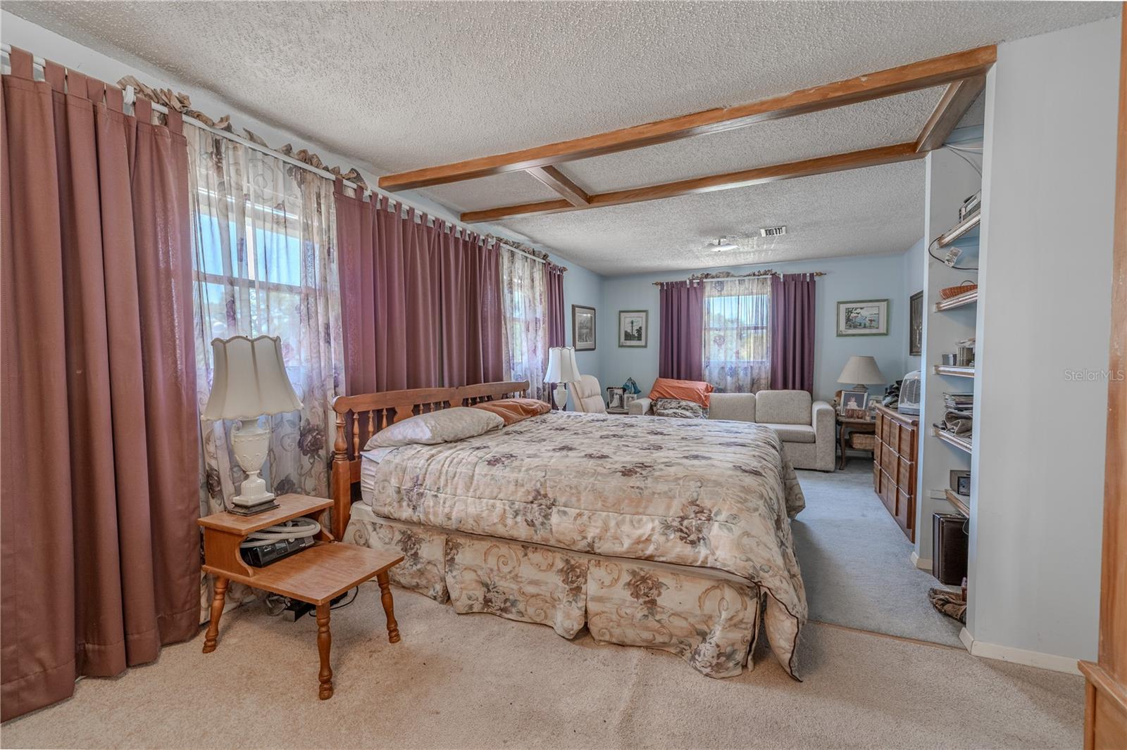 The primary bedroom has built in shelving and a sitting area.