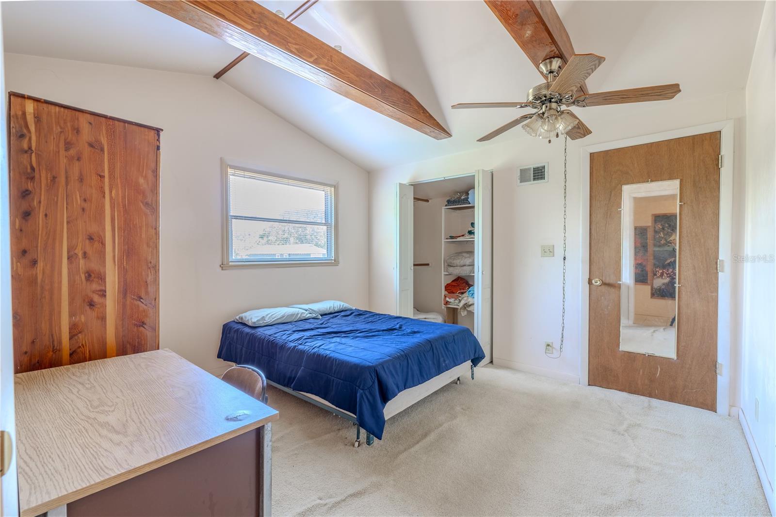 Bedroom 3 has a walk-in closet. beamed ceiling, ceiling fan and carpet.