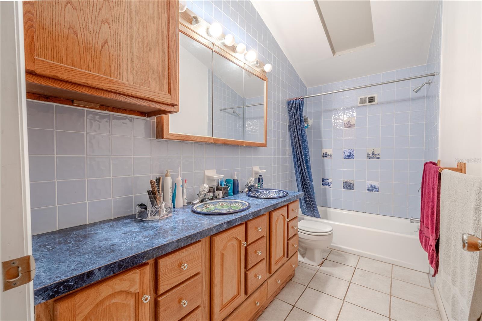 Bathroom 3 has a tile floor, mirrored wood vamity with dual sinks and a tub with shower.