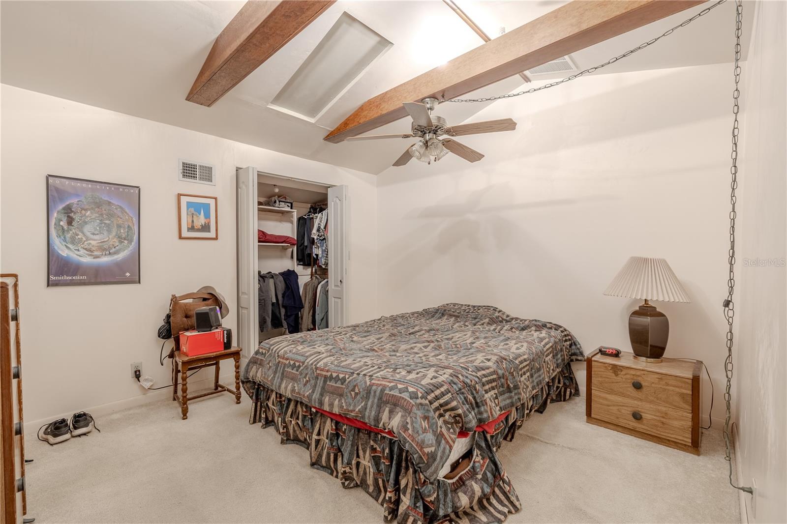Bedroom 4 features a walk-in closet, beamed ceiling and carpet.