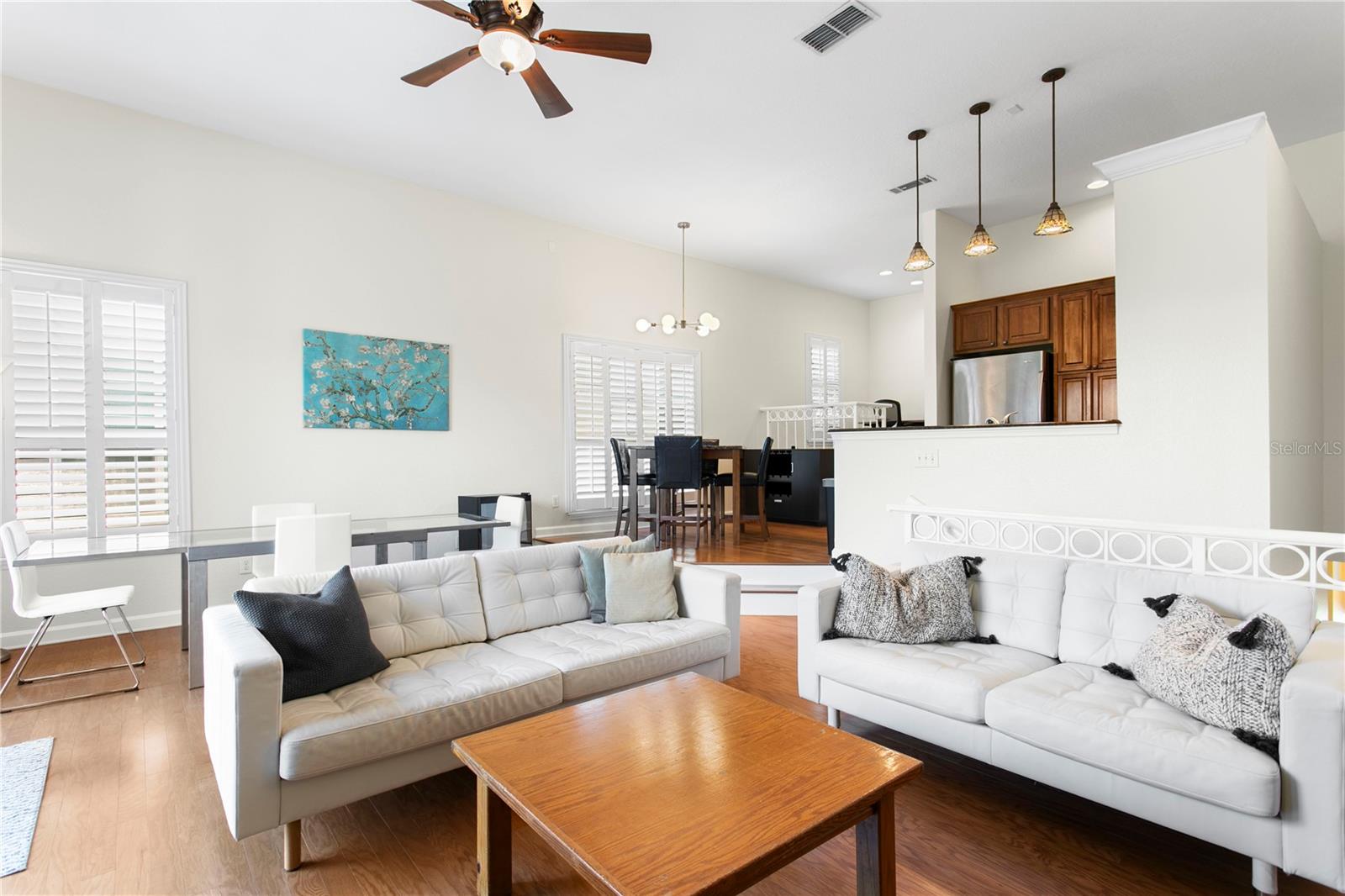 Step into the bright and airy living room with plantation shutters and wood floors that carry right into the kitchen and loft area.