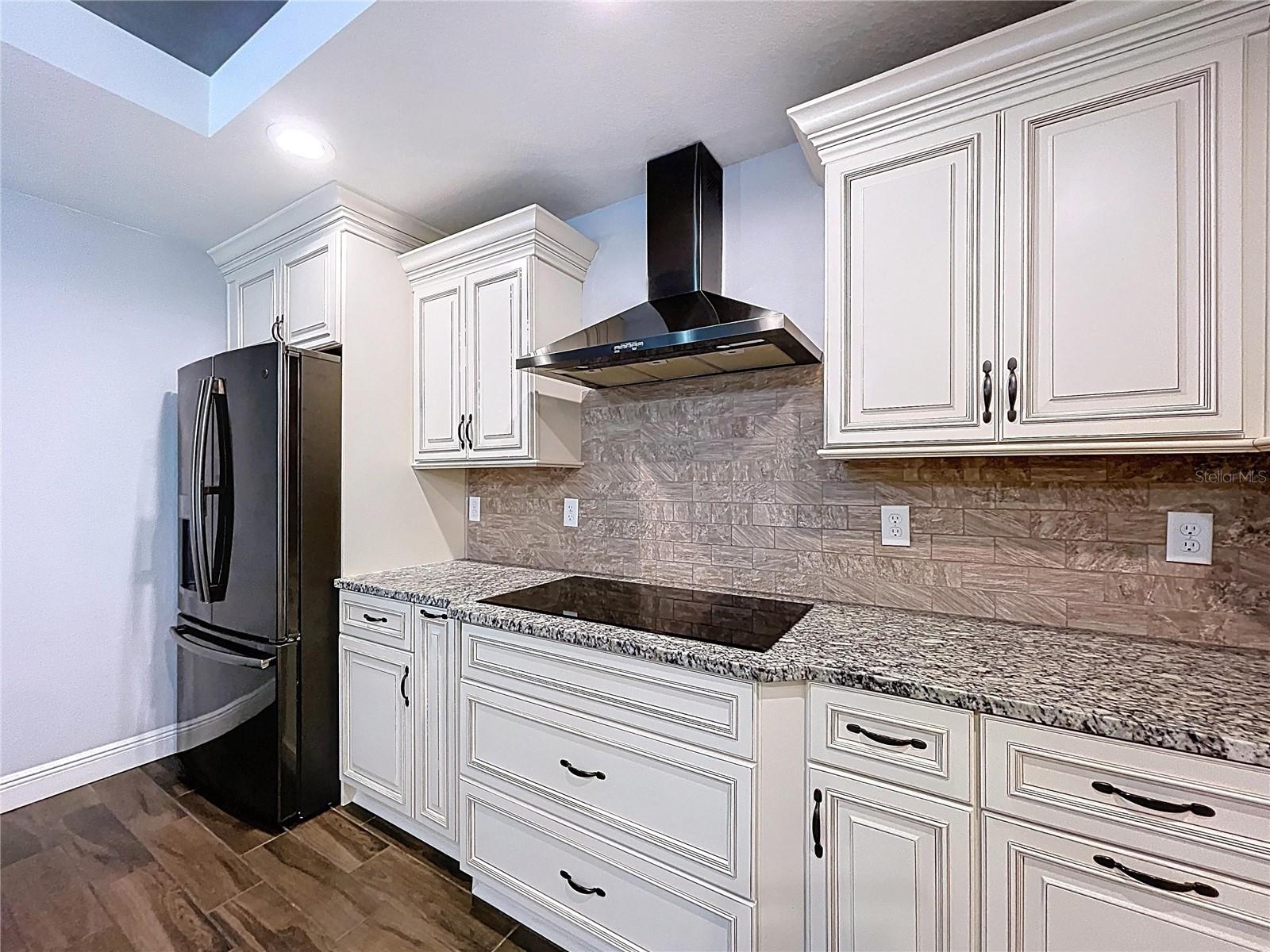 Chef-grade exhaust hood and electric cooktop.
