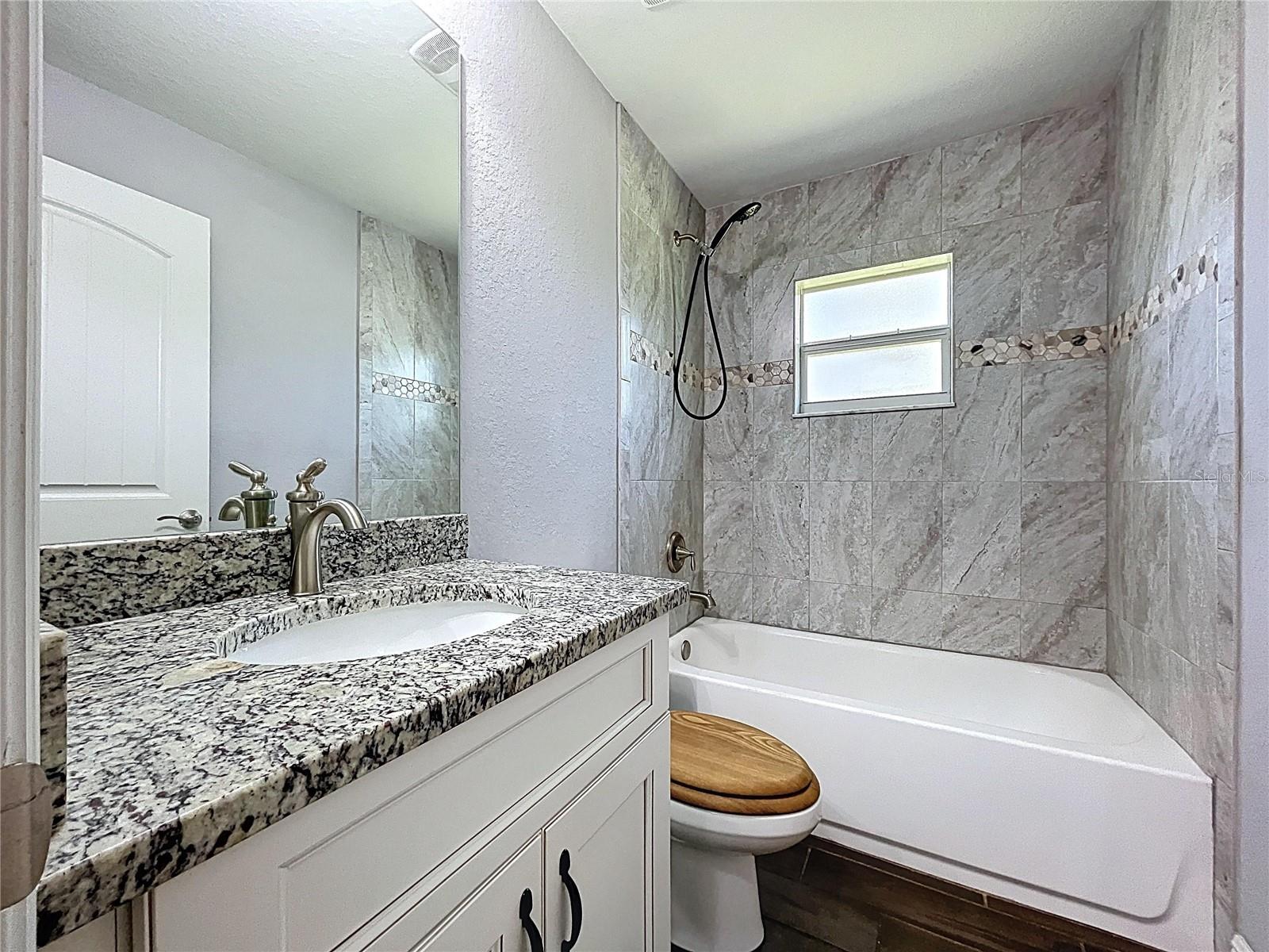 Tub and shower combo with full tile surround.
