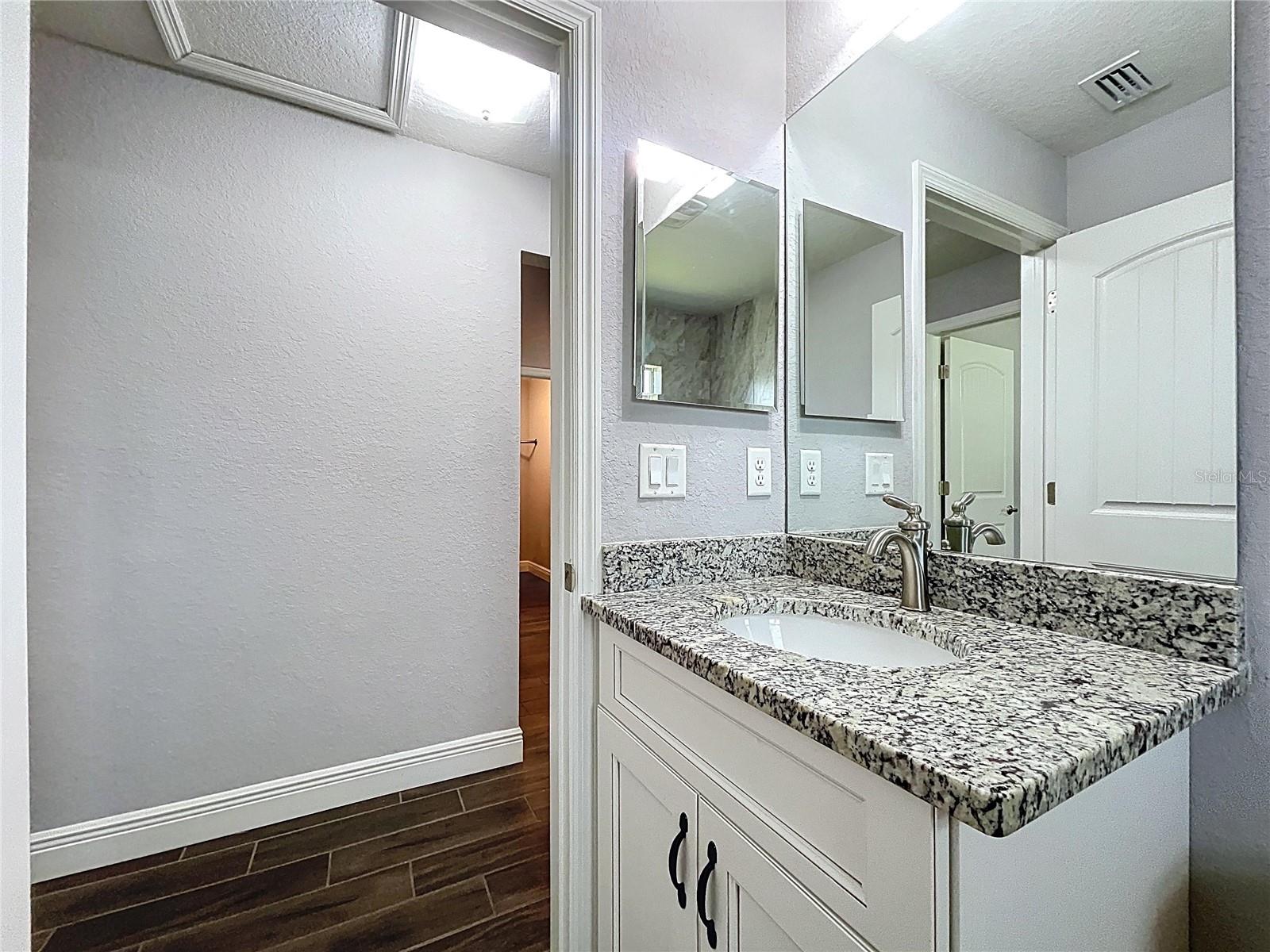 Granite vanity and shaker-style cabinets in guest bath.