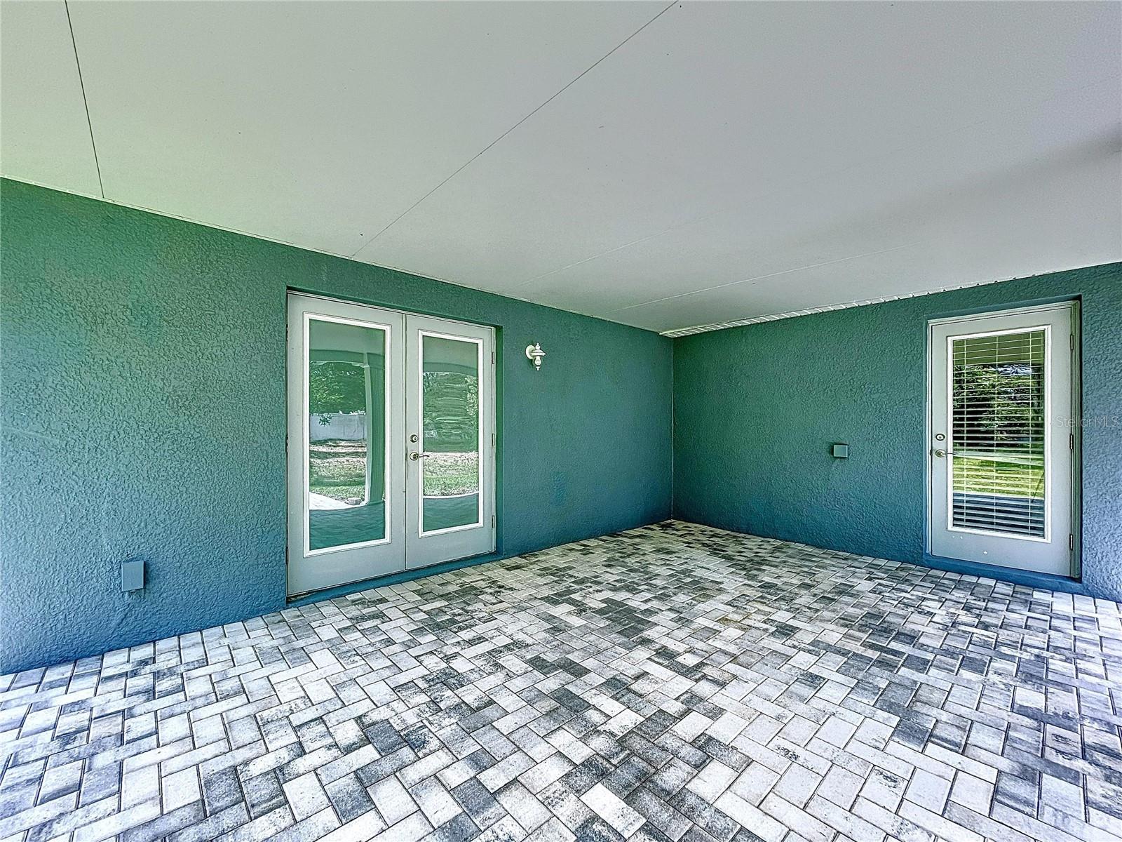 Large covered lanai with roof and pavers.