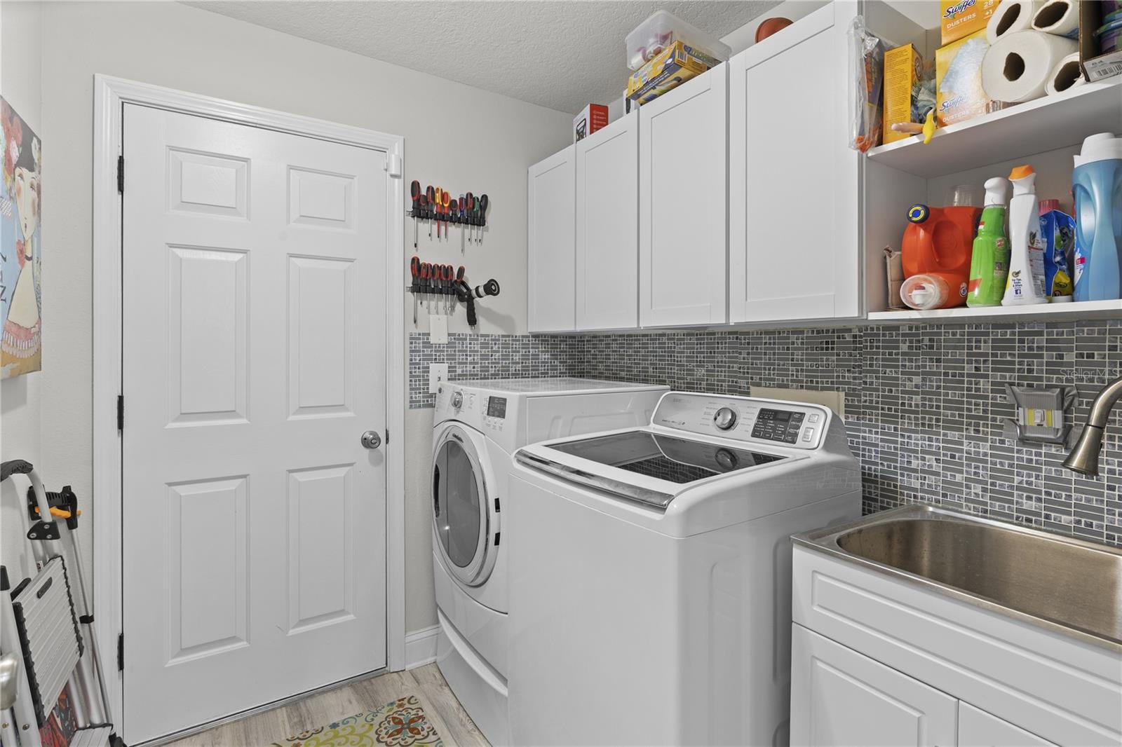 Interior laundry room with utility sink and storage cabinets