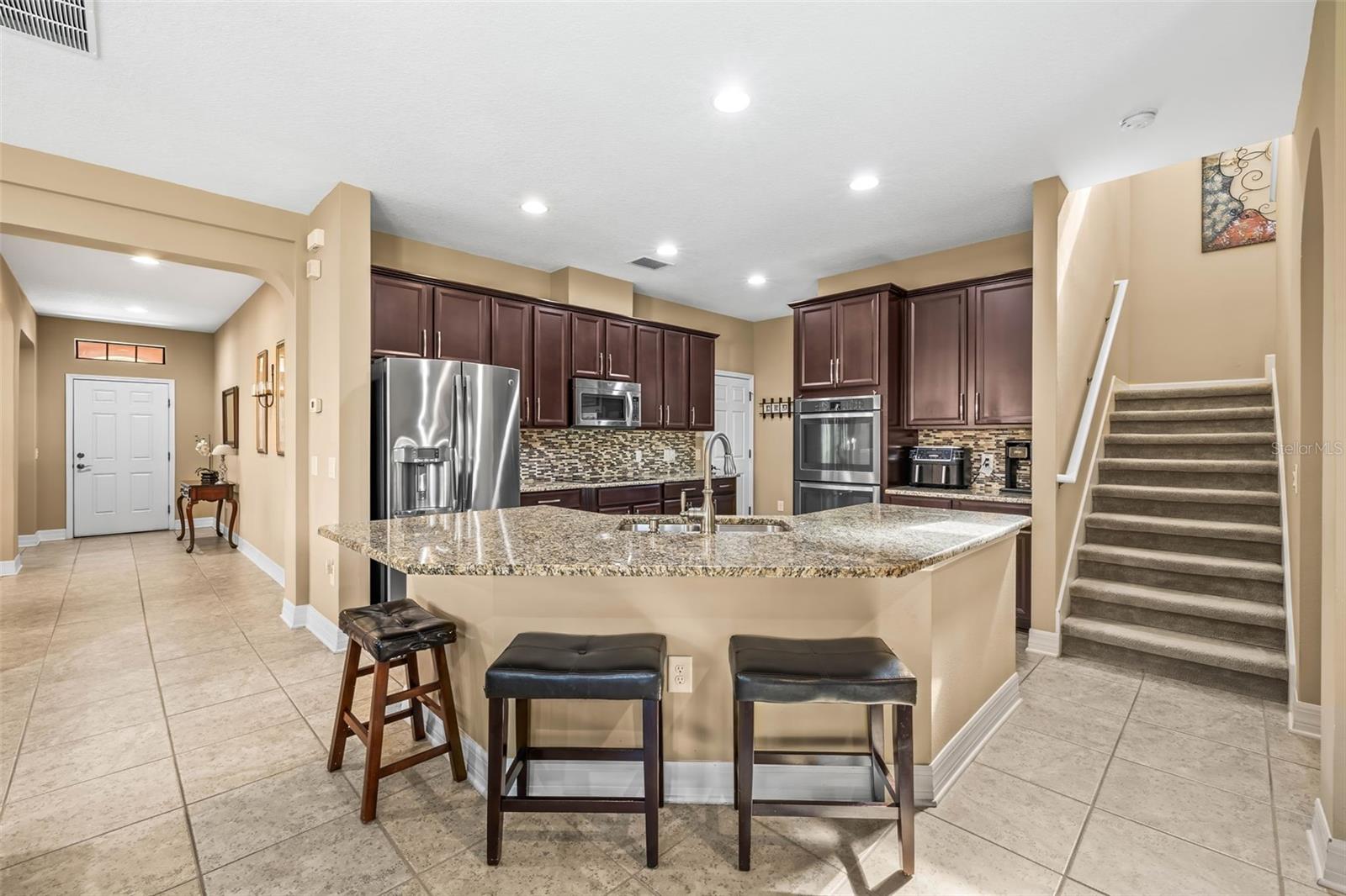 Kitchen features tall crowned cabinetry, granite countertops, huge island with seating, closet pantry and laundry room.
